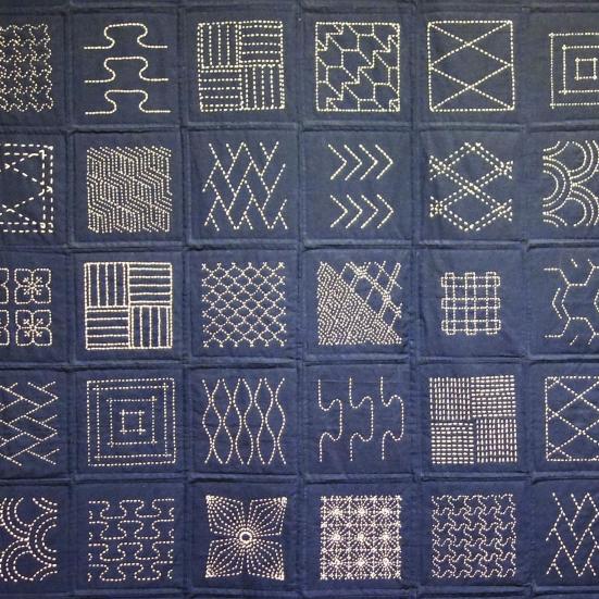 Patchwork tæppe med mønstre holdt i blå farver