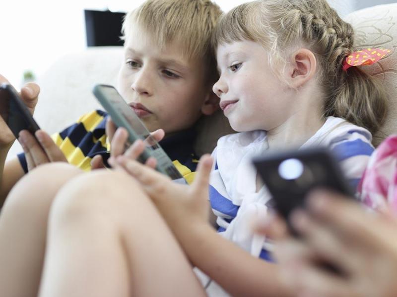 To børn sidder med deres mobiltelefoner